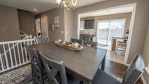 A dining area with a wooden table, chairs, a chandelier, and a view into the kitchen. - Luxury Meets Convenience *** Four Beds, Three Full Baths*** (Smithville)