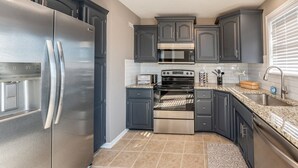 A modern kitchen with dark cabinets, stainless steel appliances, a microwave, oven, and granite countertops. - Luxury Meets Convenience *** Four Beds, Three Full Baths*** (Smithville)