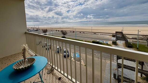 Ein Balkon mit Blick auf einen Strand, einen Parkplatz und einen klaren Himmel.
