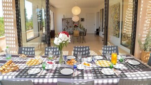 A dining area with a checkered tablecloth, set for a meal with plates, glasses, and a vase of flowers. - Villa Roka : Magnifique Villa Avec Piscine, Dans un Endroit Calme et Reposant (Essaouira)