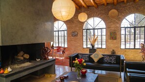 A cozy interior with a fireplace, a sofa, and a dining table with a vase of flowers. - Villa Roka : Magnifique Villa Avec Piscine, Dans un Endroit Calme et Reposant (Essaouira)