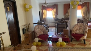 A room with checkered flooring, two ornate armchairs, a table with a red cloth, and a chandelier. - Eagles pyramids view - Foriigners only (Giza)