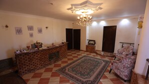 A spacious living room with a checkered floor, a central rug, a chandelier, a fireplace, and a floral armchair. - Eagles pyramids view - Foriigners only (Giza)