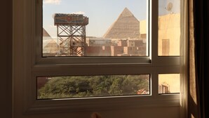 A room with a window overlooking a pyramid and a satellite dish. - Eagles pyramids view - Foriigners only (Giza)