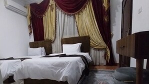 A hotel room with a double bed, a small table, a bench, and a patterned rug. - Eagles pyramids view - Foriigners only (Giza)