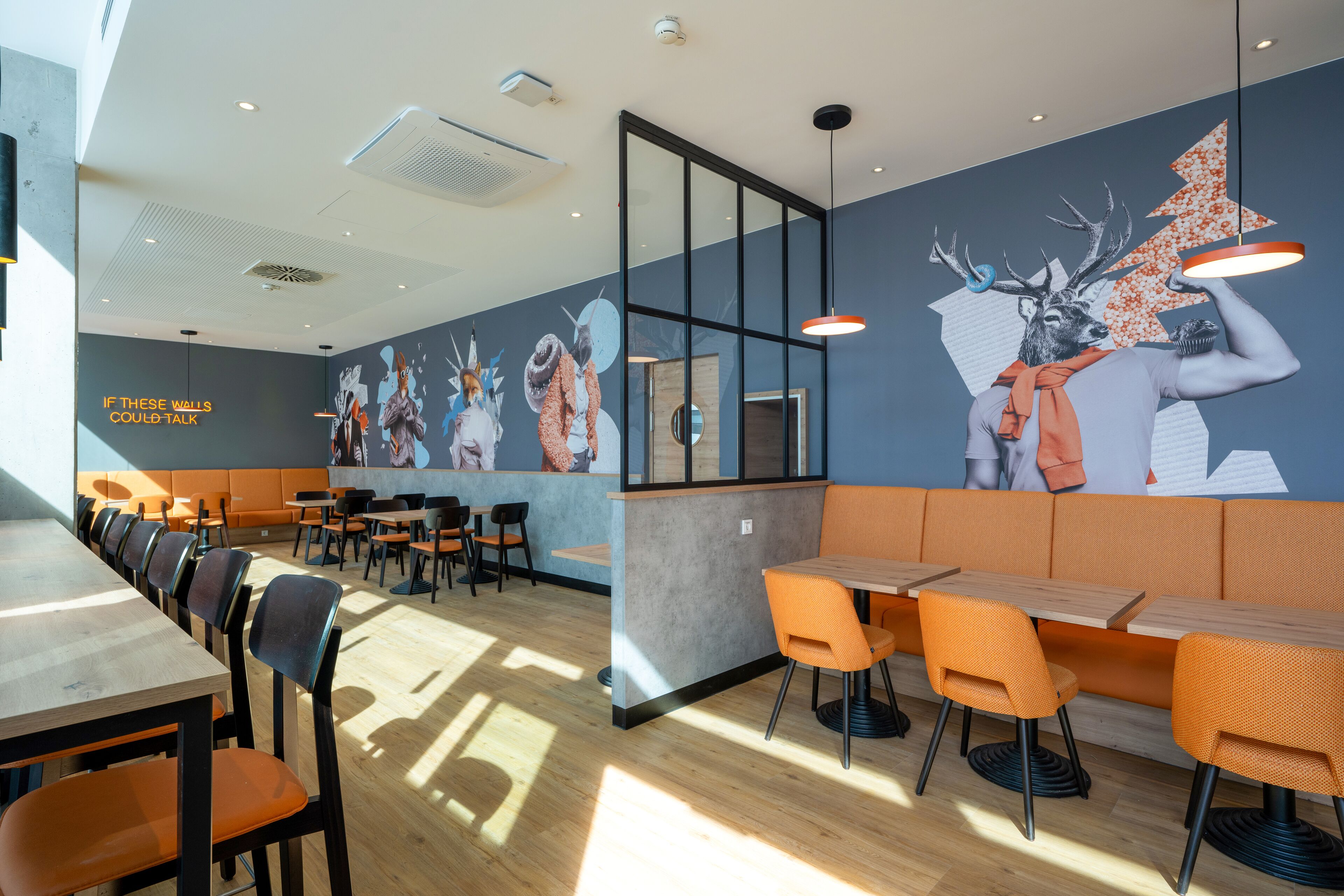 A modern restaurant interior with wooden tables and orange chairs, a large mural on the wall, and a mezzanine level with seating.