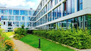 Un edificio moderno con amplios ventanales y un jardín cuidado.