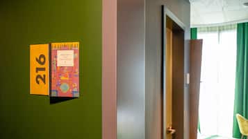 A hotel room with a green wall, a door, and a window with green curtains.