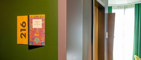 Una habitación de hotel con una pared verde, una puerta y una ventana con cortinas verdes.