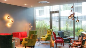 Un área de lounge moderna con diversas opciones de asientos, incluyendo sofás y sillones, y un amplio ventanal con vistas al exterior.