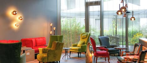 Un área de lounge moderna con diversas opciones de asientos, incluyendo sofás y sillones, y un amplio ventanal con vistas al exterior.