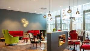 Un interior moderno con un sofá rojo, un sillón verde y sillas de madera.