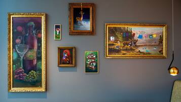 A wall with various framed artworks, including a painting of a deer, a landscape, and still life.