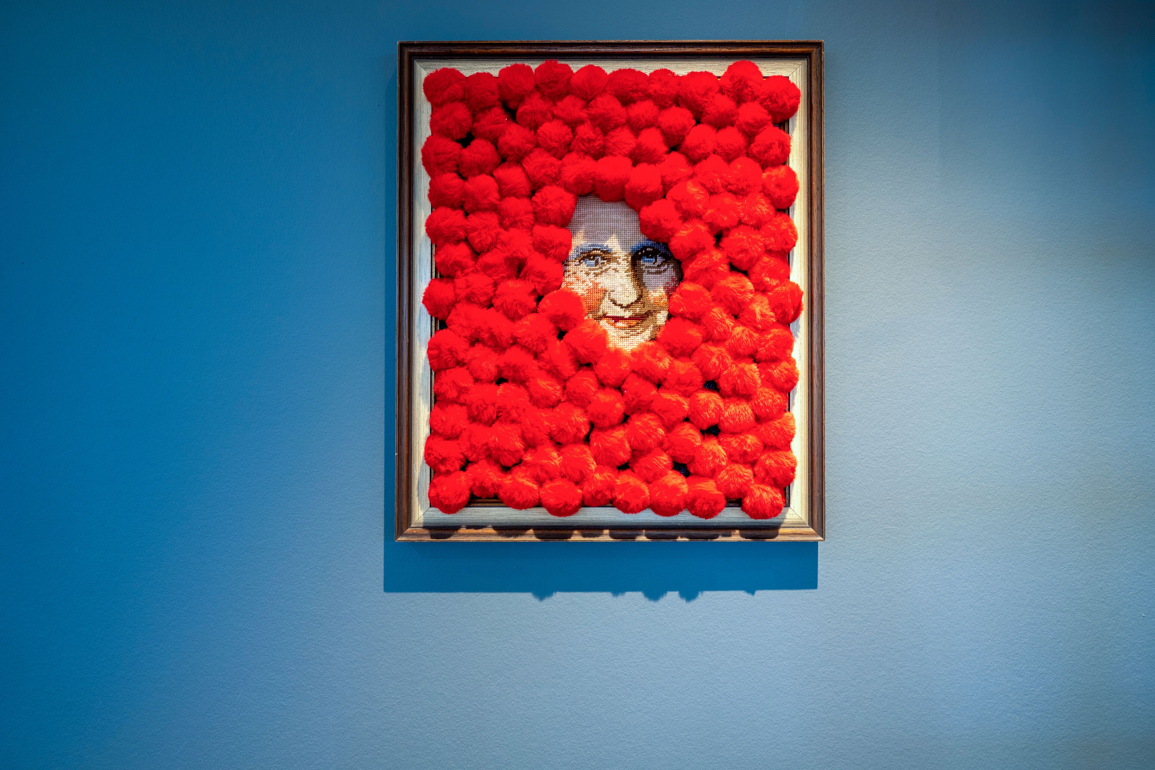 A framed artwork with a red background and a central figure.