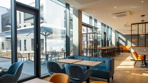 Un interior moderno con ventanas amplias, zonas de estar y un bar.