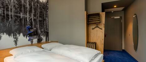 Un dormitorio con cama, un mural en la pared, un banco de madera y una puerta que da a otra habitación.