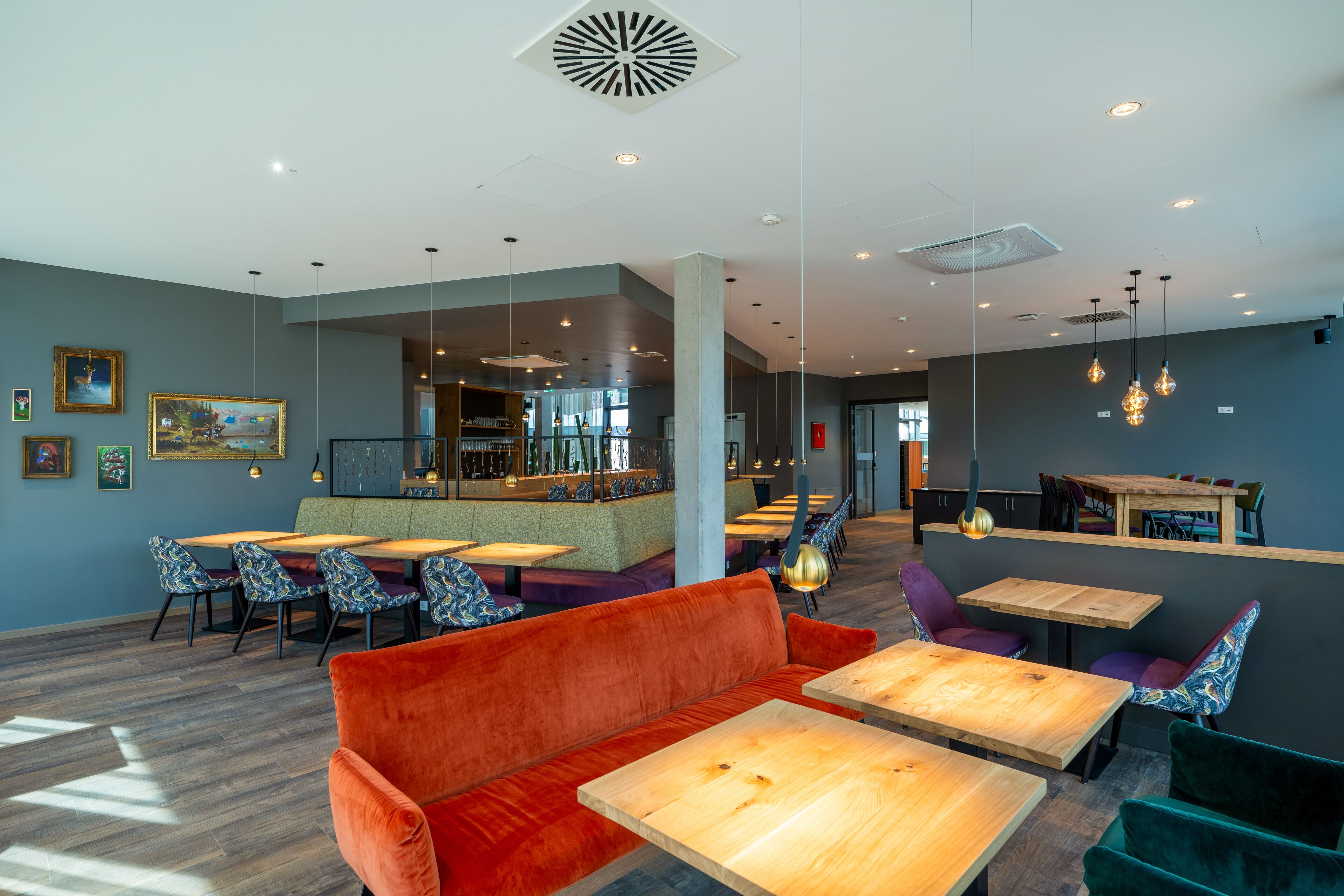 Een modern interieur met zithoeken, houten tafels en hanglampen.