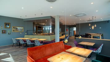 Un intérieur moderne avec des coins salon, des tables en bois et des luminaires suspendus.