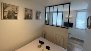 A bedroom with a bed, two paintings on the wall, a window, and a radiator. - Studio Osaka - Hyper Centre Lorient (Lorient)