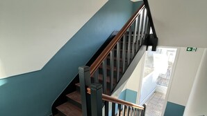 A staircase with a geometric patterned floor, a wooden handrail, and a blue accent wall. - Studio Osaka - Hyper Centre Lorient (Lorient)