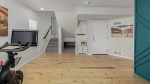 A modern interior with a staircase, a door with a picture, and a wall-mounted TV. - Monthly Stays! Denver Chile House (Commerce City)