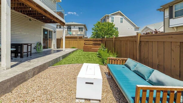 A residential backyard with a patio, a white outdoor heater, a wooden fence, and a green lawn. - Monthly Stays! Denver Chile House (Commerce City)