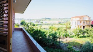 Een balkon met uitzicht op een woonwijk, inclusief huizen en groen.