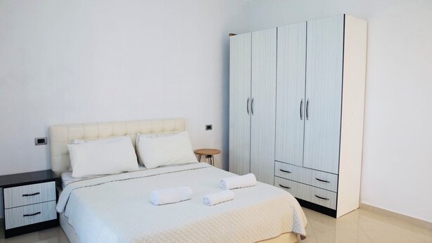 Een slaapkamer met een bed, nachtkastjes, een garderobe en een klein rond tafeltje.