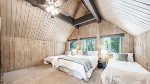 Une chambre avec deux lits, des murs en bois, un plafond en pente et de grandes fenêtres.