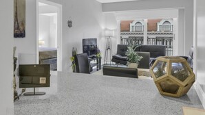 Een moderne keuken met granieten aanrechtbladen, een eethoek met een zwarte bank en een salontafel, en een woonkamer met een leren bank in zwart en een televisie.