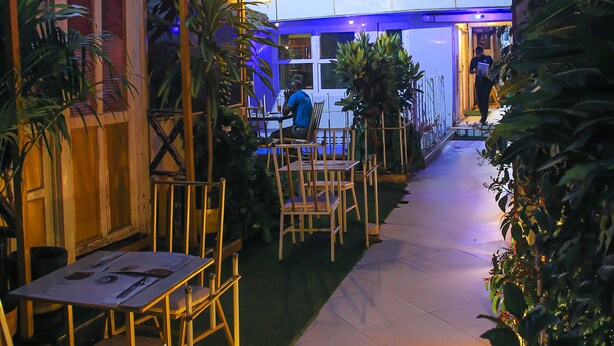 An outdoor dining area with tables and chairs, surrounded by potted plants. - AFRIKANDO ROYAL CASTLE (Dar es Salaam)