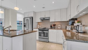 A modern kitchen with white cabinets, stainless steel appliances, and granite countertops.