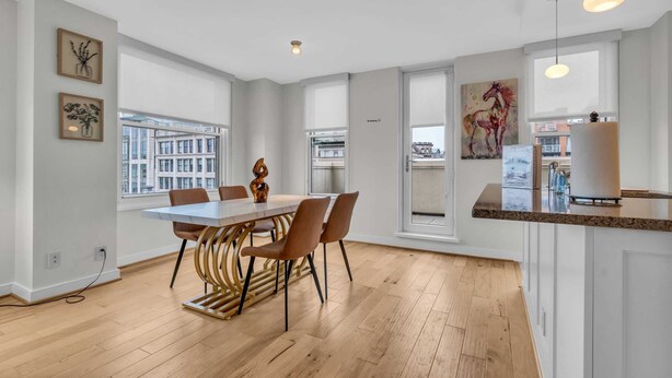 A modern kitchen with a large island, white cabinetry, and a view of the city.