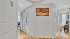 A hallway with wooden flooring, white walls, and a painting.