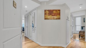 Un couloir doté d’un plancher en bois, de murs blancs et d’un tableau.