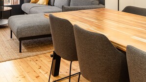 Ein modernes Wohnzimmer mit einem Holzesstisch, grauen Sofas und einer Stehlampe.