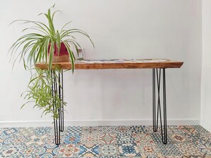 A wooden table with metal legs, a potted plant, and patterned floor tiles.