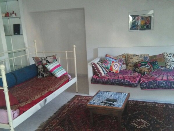 A room with a bed, a sofa, a small table, and a wall-mounted picture.