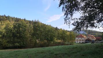 A rural landscape with a traditional stone building, surrounded by lush greenery and a clear sky.