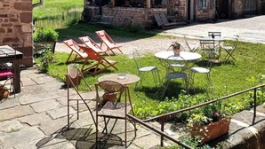 A rustic stone building with a wooden porch and outdoor seating area. - Maison d'hôtes de charme - Ancien moulin en pleine nature - La Paulusmühle (Soucht)