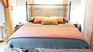 Ein Bett mit Metall-Kopfstück, Holzwänden und rustikalem Boden.