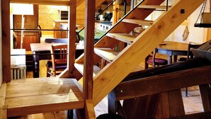 A wooden staircase leading to a loft area with a kitchen and dining space. - Maison d'hôtes de charme - Ancien moulin en pleine nature - La Paulusmühle (Soucht)