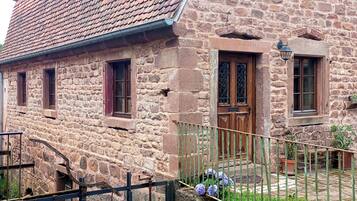A stone building with a tiled roof, a wooden door, and a small window.