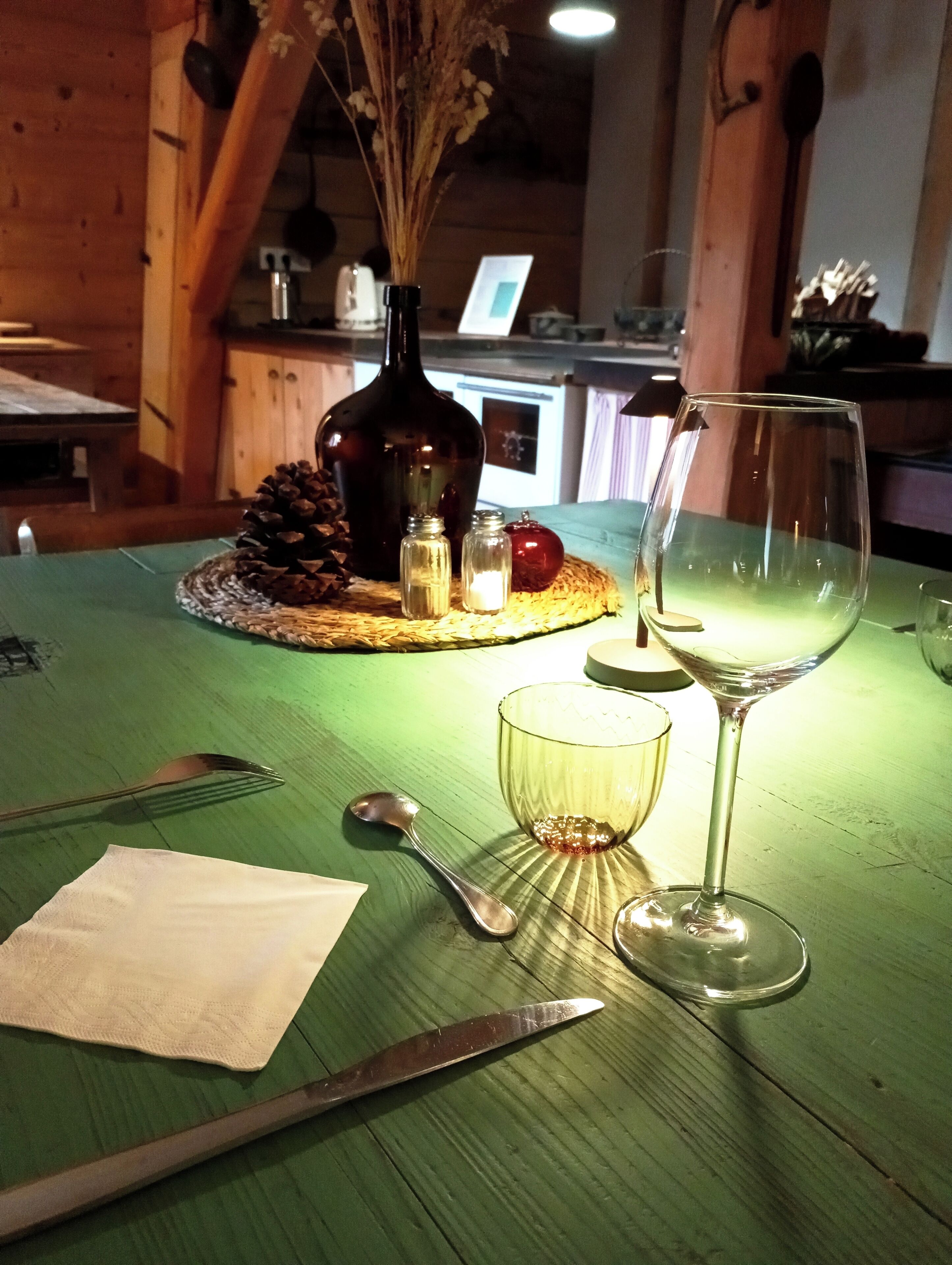 A table set with a knife, spoon, glass, and a bottle.