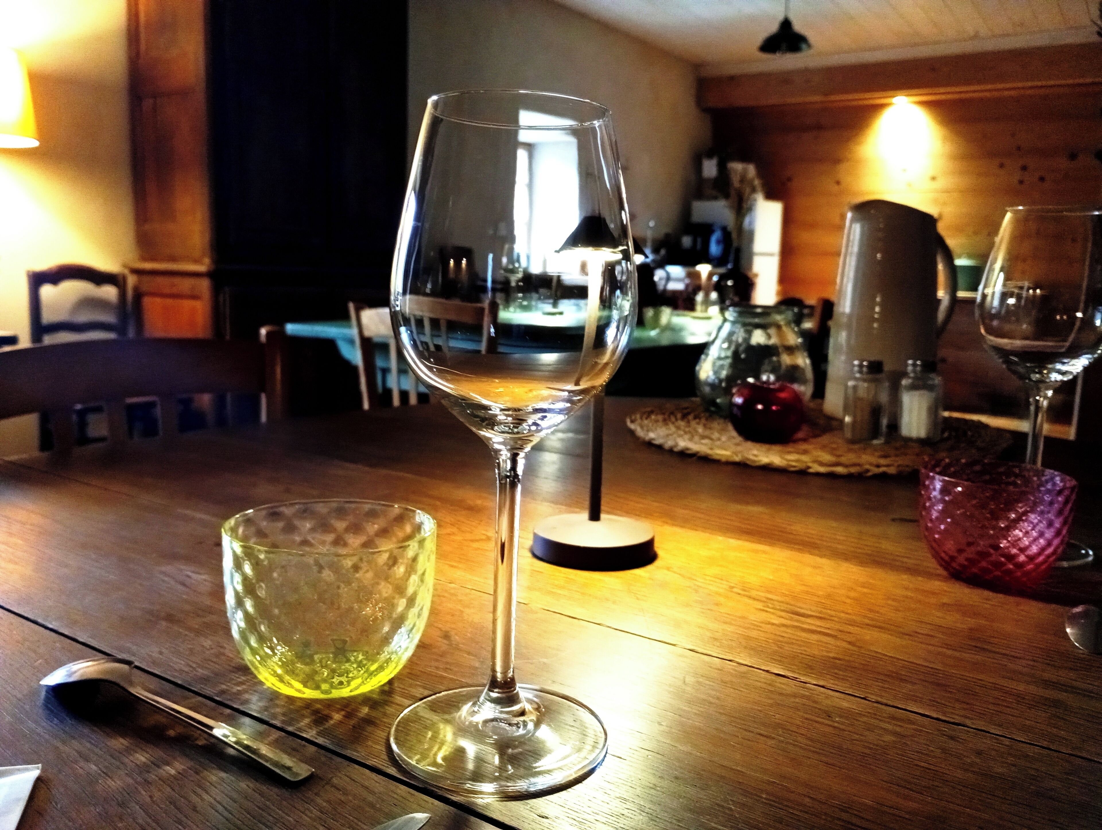 Une table à manger avec un verre à vin et un saladier en verre.