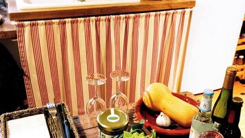 A kitchen counter with a cutting board, knife, bottle, and various food items.