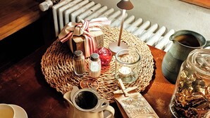 A cozy dining setup with a woven placemat, candles, a mug, and a variety of snacks and condiments. - Maison d'hôtes de charme - Ancien moulin en pleine nature - La Paulusmühle (Soucht)