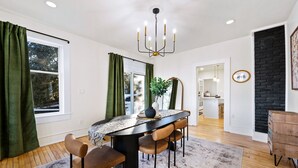 A modern dining area with a large table, chairs, and a chandelier.