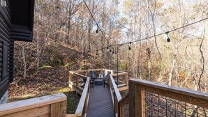 A wooden deck with chairs and a table, surrounded by trees.