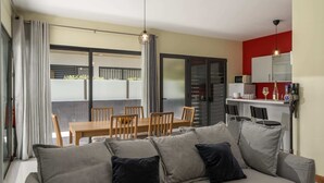 A modern living room with a grey sofa, wooden dining table, and chairs. - Vacation Home in Porto Santo, Villa Girassol (Porto Santo)